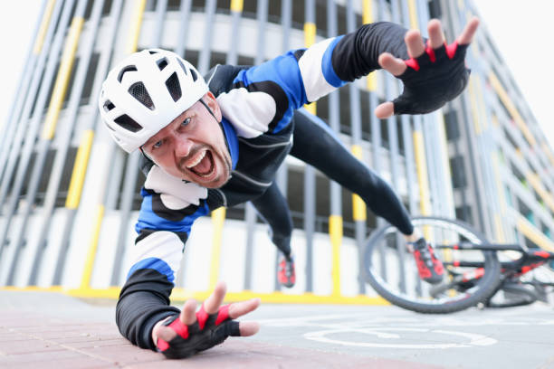 le jeune cycliste mâle utilisant le casque et l’équipement protecteur est tombé du vélo et du portrait de vol - wrong injury photos et images de collection