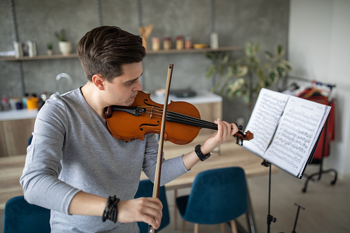 Violinist standing in front of music stand and playing violin at home