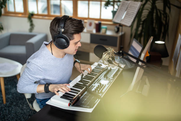 Young musician making music in his home recording studio Young musician making music in his home recording studio making music stock pictures, royalty-free photos & images