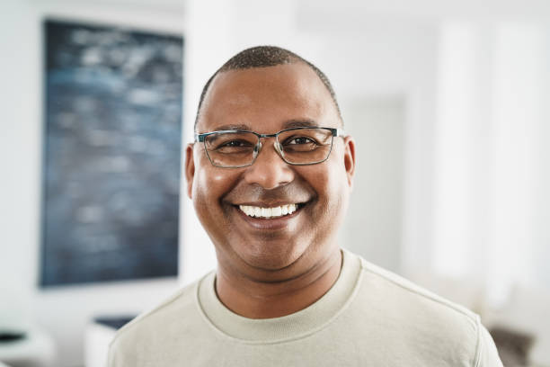 Happy african man looking at camera indoors at home - Focus on face stock photo