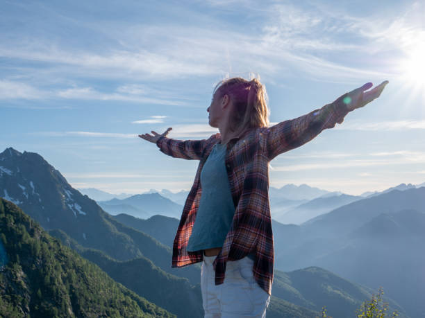 istock Hiker stands arms out on mountain top 1312106384