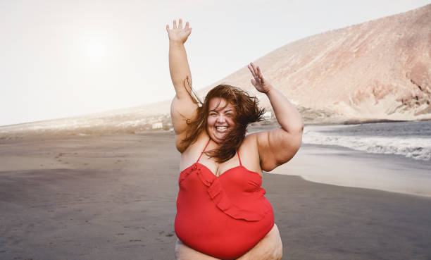 istock Curvy overweight woman smiling with beach on background - Focus on face 1312107556