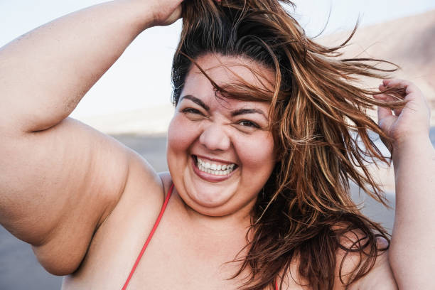 istock Curvy woman smiling on camera wearing bikini with beach in background - Focus on face 1312107572