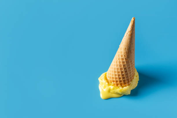 istock Melted yellow ice cream cone creative pastel blue background 1312107895