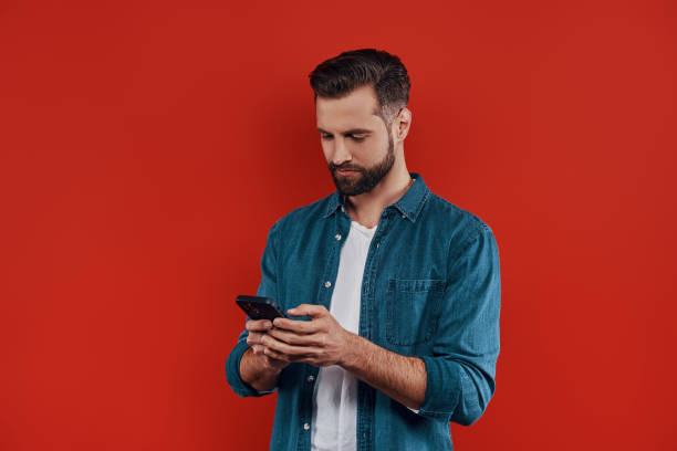 joven guapo con ropa casual - marcar usar el teléfono fotografías e imágenes de stock