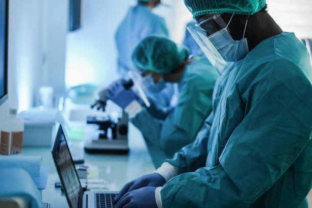 istock Medical workers working with computer and micoroscope inside hospital laboratory during coronavirus outbreak - Focus on african man face 1312110052
