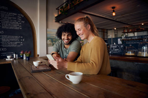 istock Smiling couple looking at smartphone sitting in modern cafe 1312110354