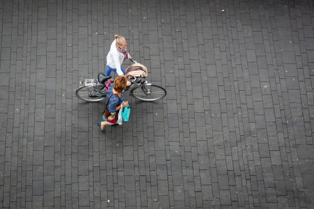 Enschede, Overijssel, Netherlands, may 1st 2012, High angle view with blurred motion of two (caucasian) women walking alongside the market on the 'Van Heekplein' market square downtown Enschede - one holding shopping bags and the other holding a bicycle - the square holds one of the largest weekly markets in the country and has a large parking garage underneath
