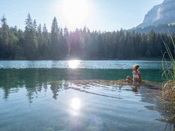 istock Woman sunbathing on a rock inside alpine lake 1312113252
