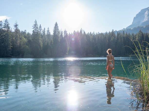 istock Woman sunbathing on a rock inside alpine lake 1312113328