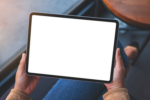 una mujer sosteniendo tableta digital con pantalla de escritorio blanco en blanco - agarrar fotografías e imágenes de stock