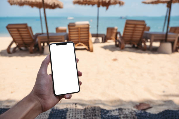 istock a man holding mobile phone with blank desktop screen while sitting on the beach 1312114191
