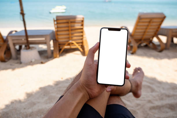 istock a man holding mobile phone with blank desktop screen while sitting on the beach 1312114216