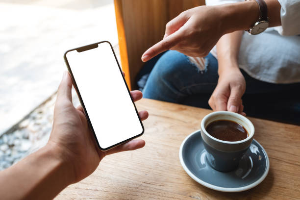 istock a woman pointing at a white mobile phone with blank black desktop screen in a man's hand 1312114330