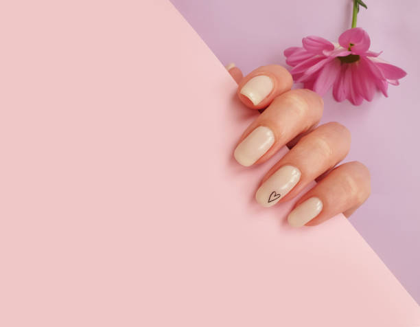 istock female hand beautiful manicure, flower on colored background 1312114382