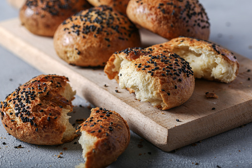 Freshly baked buns ​with black cumin seeds on gray background.