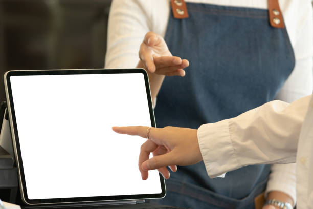 istock Digital tablet with blank screen and hand pointing to screen in restaurant. 1312120714