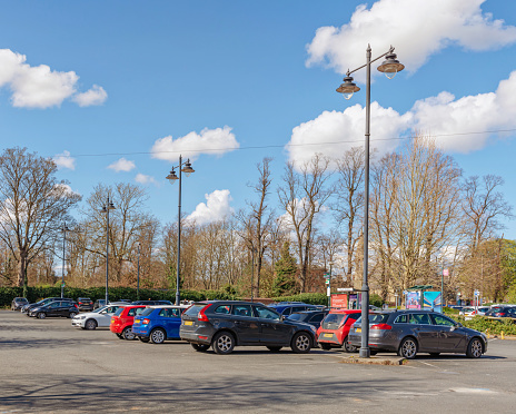 York, UK. April 9, 2021.  York, UK. April 9, 2021.  A typical view of a city car park.  Cars are parked in neat rows and tall lampposts tower above.  There are trees in the background.