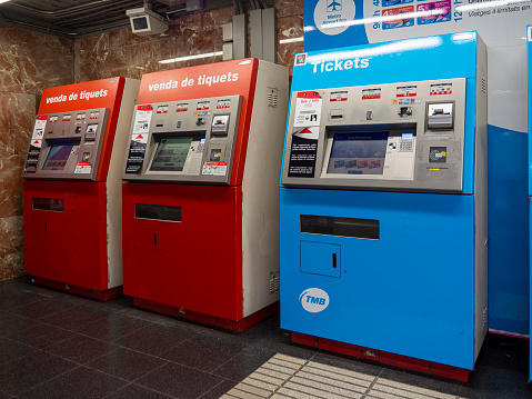 Barcelona, Spain - April, 2021: Three ticket machines in a subway station in Barcelona. Red and blue machines for public transport and airport tickets. Touch screen for buying transport cards.
