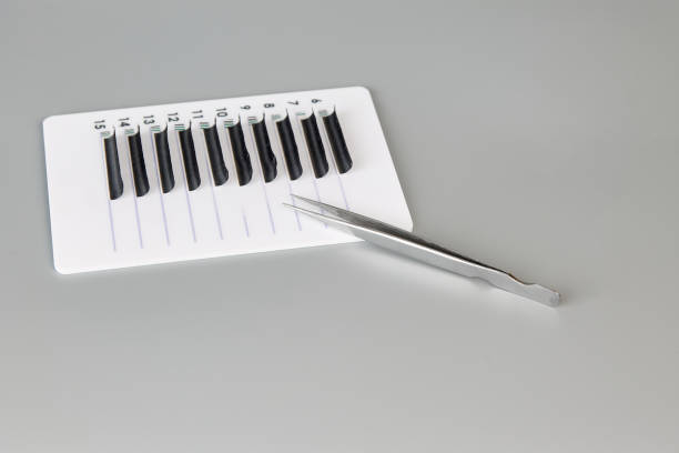 Tablet with false eyelashes and tweezers on a gray background. Tablet with false eyelashes and tweezers on a gray background. Cosmetic accessories for eyelash extensions clump eyelashes stock pictures, royalty-free photos & images