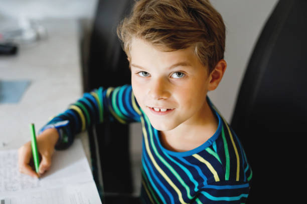 istock Hard-working happy school kid boy making homework during quarantine time from corona pandemic disease. Healthy child writing with pen, staying at home. Homeschooling concept 1312123681