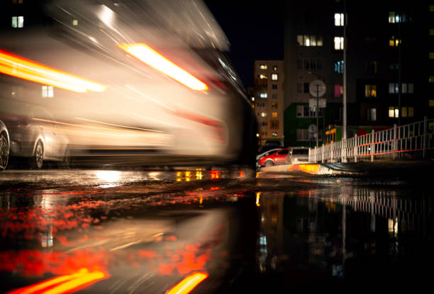 a white car on the road with a blurred traffic background. a white car on the road with a blurred traffic background. Lower camera angle, on a city street. street racing stock pictures, royalty-free photos & images