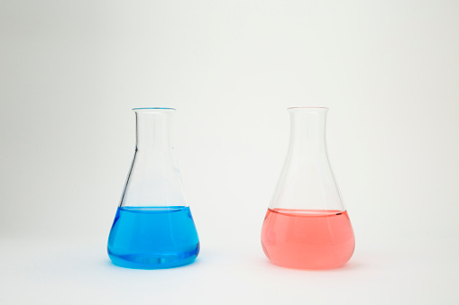 Scientific laboratory flask filled with blue and pink liquid on white background.