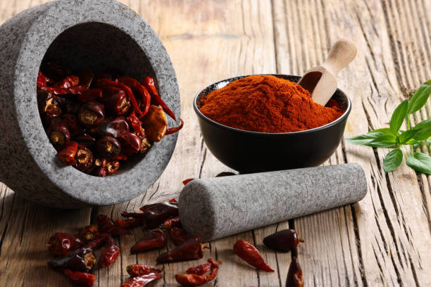 Mortar and Pestle Marble Mortar and Pestle with dried Chilli Peppers and ground Powder with a rustic wood background and copy space on right. Taken with Canon R5 producing 45 Megapixels chilli powder stock pictures, royalty-free photos & images