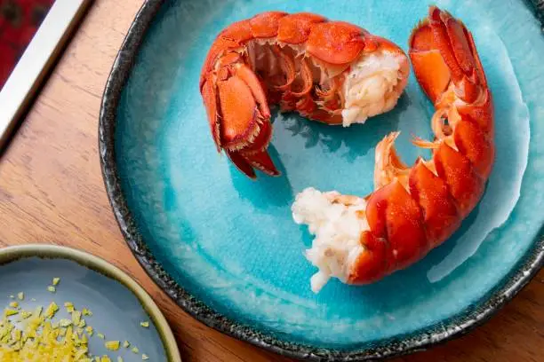 Plate of lobster with lemon zest on wood