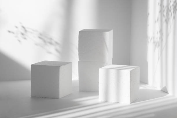 istock 3d podium, for presentations of packaging, cosmetics. Three white square scenes, of different heights, against background of clean walls with hard shadows from flowers. The concept of the beauty 1312129191