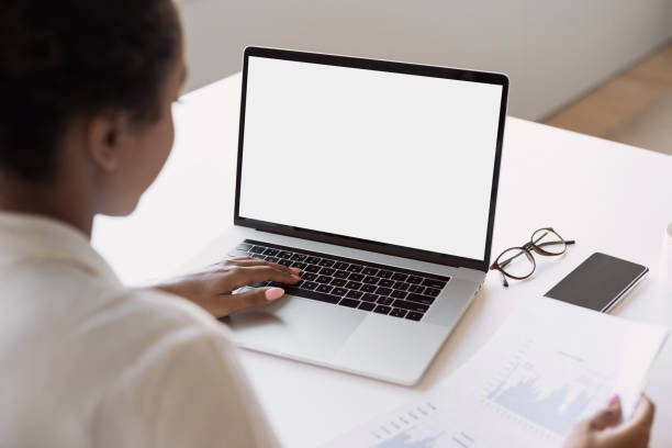 istock Young woman using laptop in office, white blank empty screen mock up 1312129385