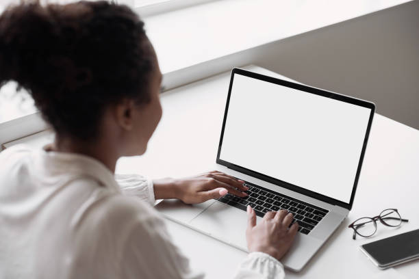 istock Young woman using laptop in office, white blank empty screen mock up 1312129427