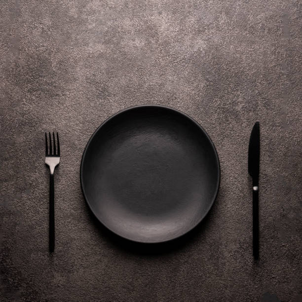 istock black empty plate, fork and knife on a dark textured table, A concept for a restaurant or coffee shop menu bar copy space flat lay minimalism still life 1312133499