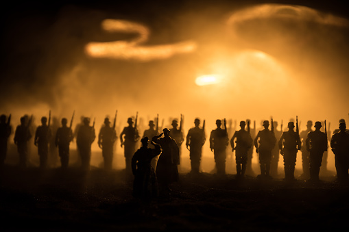 War Concept. Military silhouettes fighting scene on war fog sky background, World War Soldiers Silhouette Below Cloudy Skyline At night. German soldiers in ranks. Selective focus