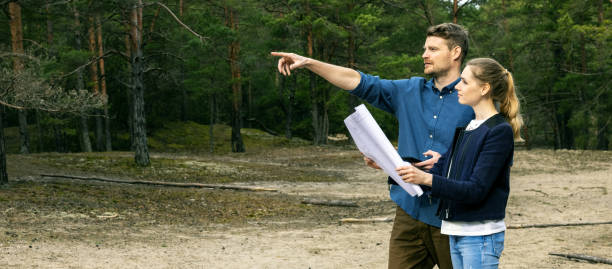 istock young couple choosing a plot of land for forest lodge construction. banner copy space 1312137936