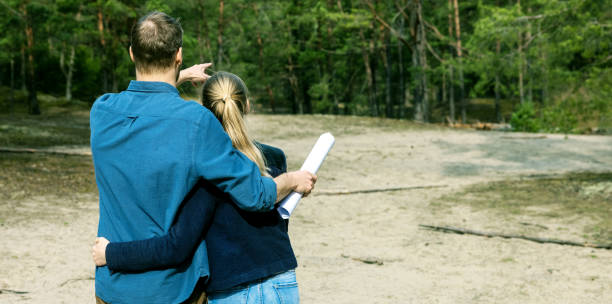 young couple choose a plot of land for dream house construction in forest. copy space