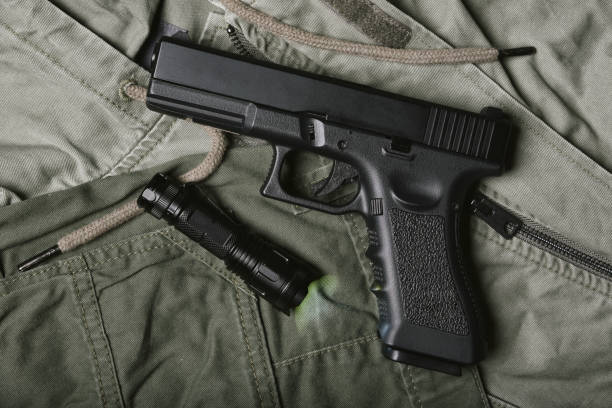 Weapons and military gun equipment for army with tactical flashlight, Semi-automatic handgun, 9mm pistol on green military uniform background.