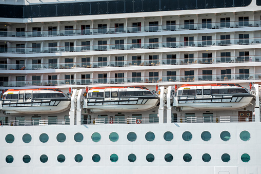 Cruise ship sails across a beautiful calm ocean. Deck chairs are laid out ready for relaxtation.