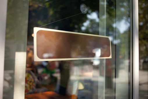 Blank sign on glass door with coffee shop background