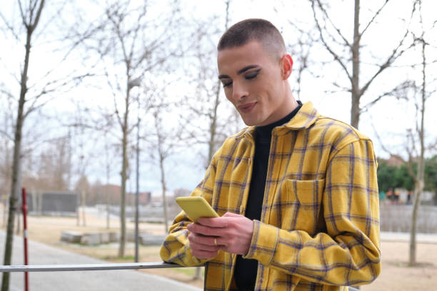 istock Young non binary person checking his smartphone and smiling. Make up androgynous person. 1312141440