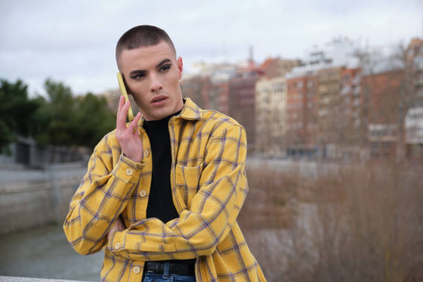 joven persona no binaria hablando en un teléfono inteligente molesto. maquínate a una persona andrógina. - non verbal communication fotografías e imágenes de stock