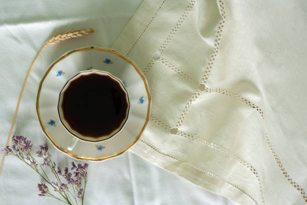 Cup of coffee on a white sheet. Coffee in bed. Flat lay.