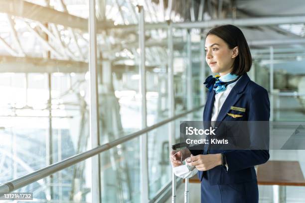 Cabin Crew Or Air Hostess Holding Face Mask Standing In Passenger Terminal At The Airport During The Covid Pandemic To Prevent Coronavirus Infection New Normal Lifestyle In Air Transport Concept Stock Photo - Download Image Now