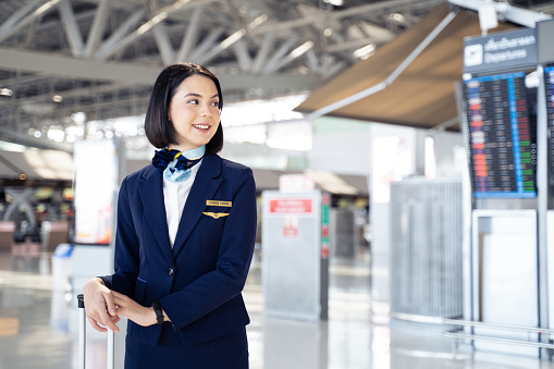 Portrait of beautiful Caucasian flight attendant staff smiling and looking to the right with confident face and happiness in airport terminal. Feeling welcome all customer or passenger to the airplane