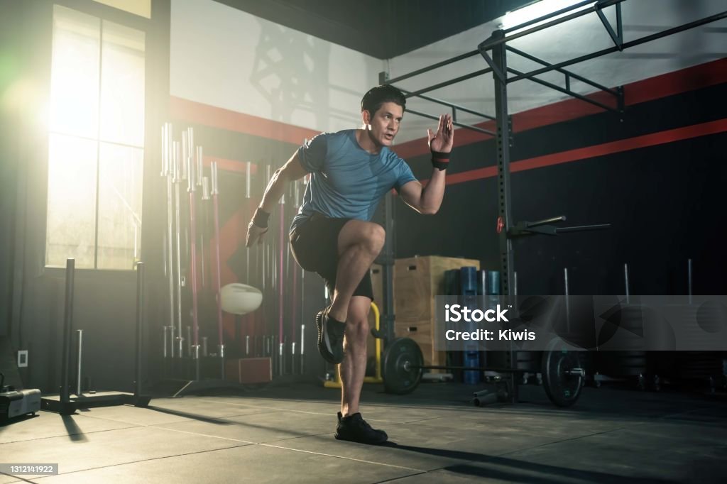 Strong young athlete fit man running in fitness gym. The man with sportswear showing his strength muscular in body. Bodybuilding exercise and sport workout training concept. Exercising Stock Photo