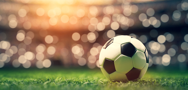 Football soccer ball on grass field on stadium, evening match.