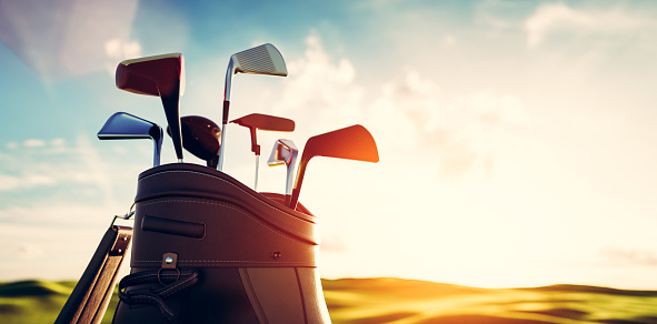 Golf clubs in bag at golf course resort at sunset