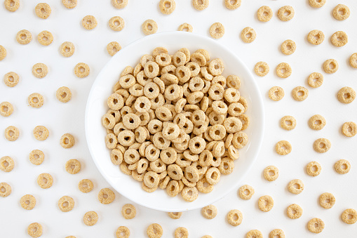 bowl with cereal cheerios isolated on white background, cereal cheerios crumbled around the cup, view from above