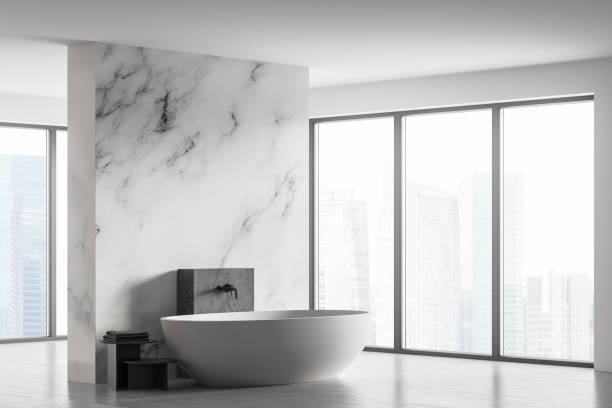 istock White marble bathroom with white bathtub and towels near window 1312145018