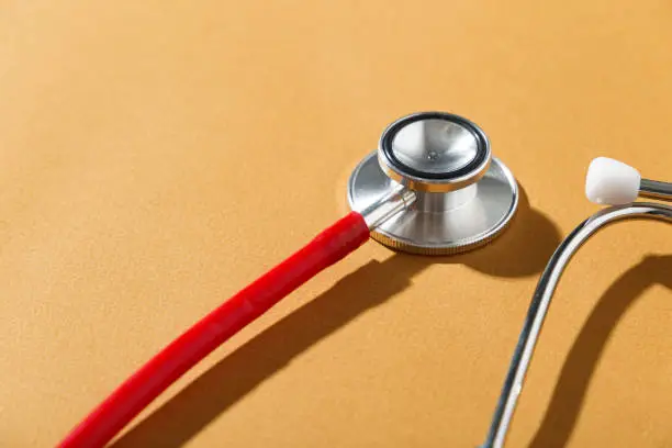 Red stethoscope on orange background, copy space